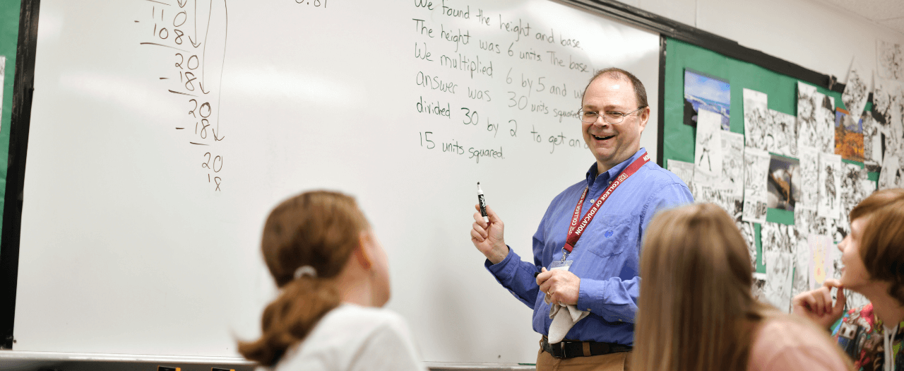 EKU student teacher, Michael Thomas, stands at whiteboard to teach elementary children math.