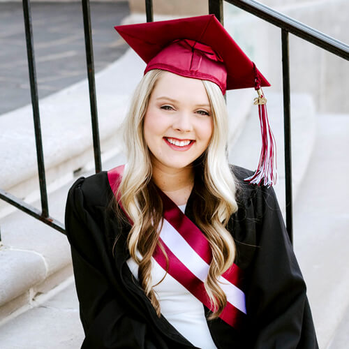 EKU graduate Taylor Newton poses in her cap and gown on the steps of Keen Johnson.