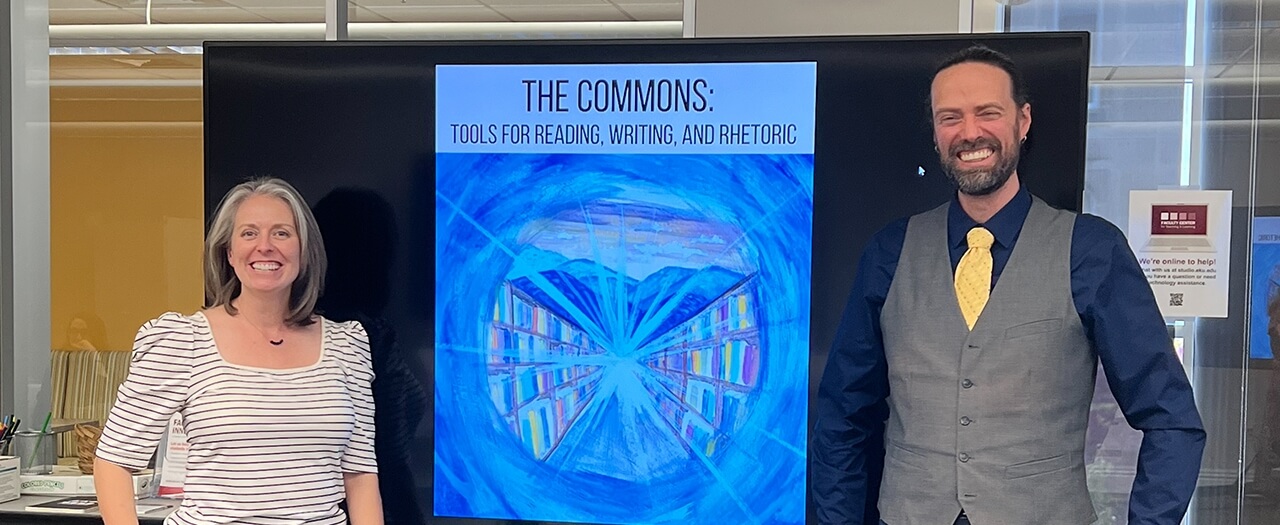 EKU faculty members Dr. Dominic Ashby and Dr. Jill Parrott pose in front of large image of their book in the library.