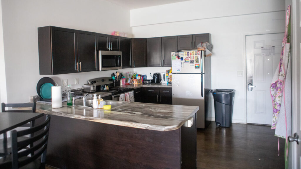 a dining table and kitchen with a stove and microwave and refrigerator in a Grand Campus apartment