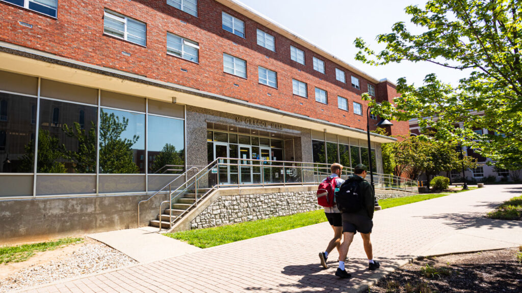 students walk past the front entrance of McGregor Hall which has traditional rooms and community bathrooms