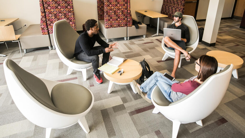 students sitting around a table and talking in North Hall with booths along the wall