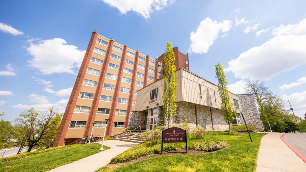 an entrance to multi-story Walters Hall with green trees growing around it