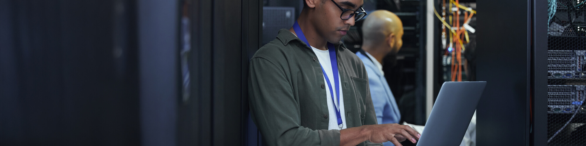 student holds a laptop while in a room of network servers