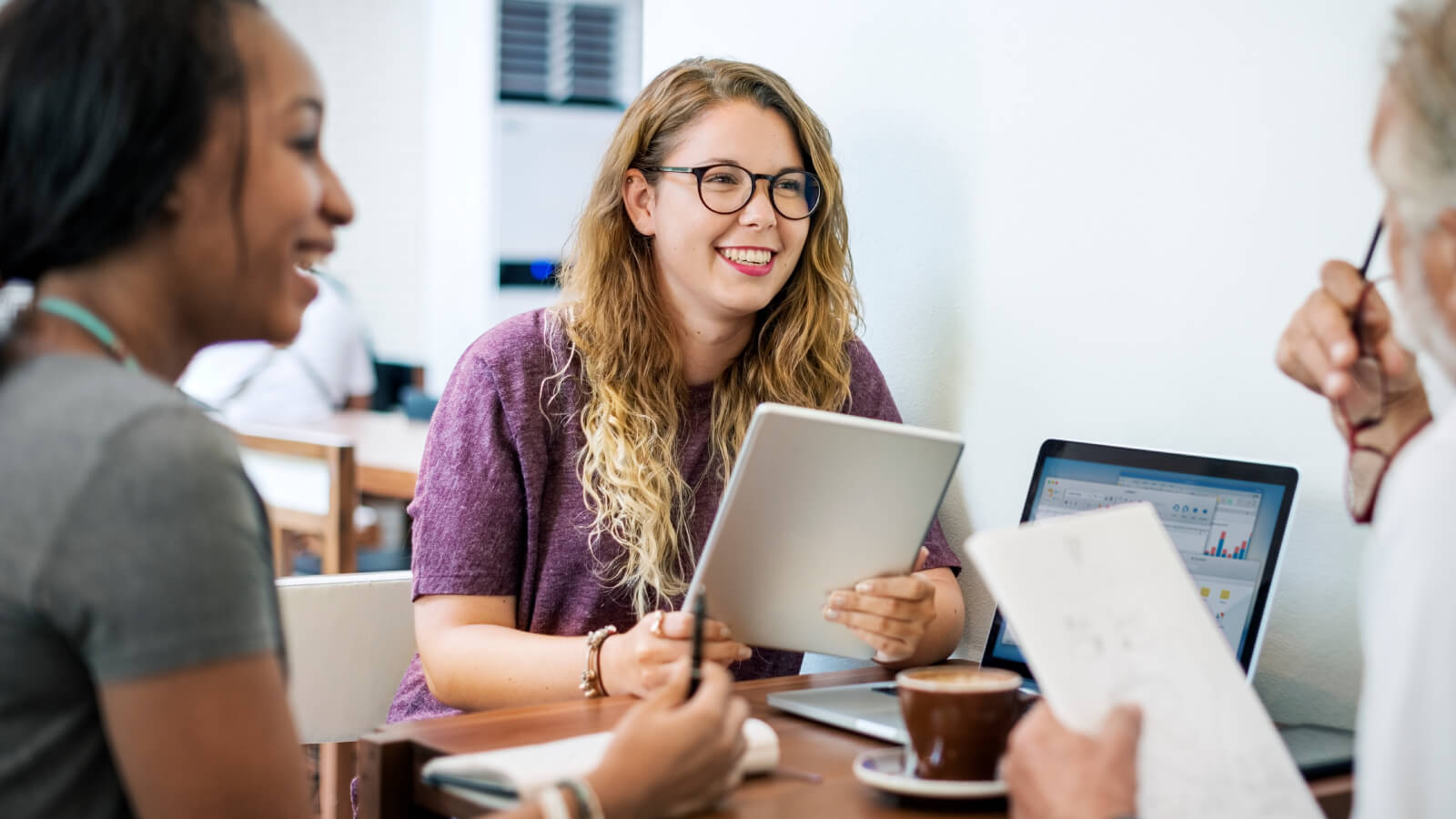 two students at a table talking with an advisor with laptop